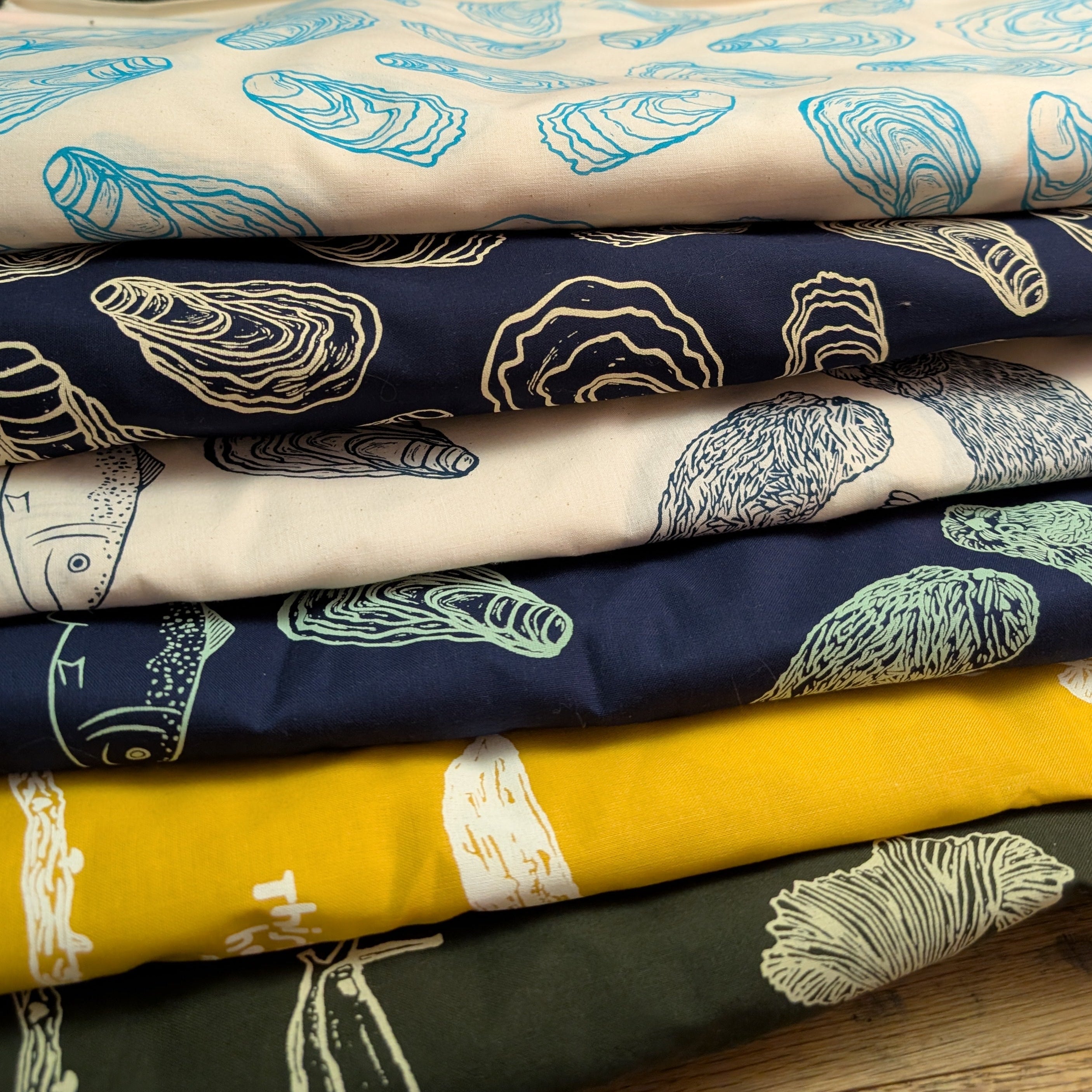 Stack of cotton bandanas with printed patterns on a wooden surface
